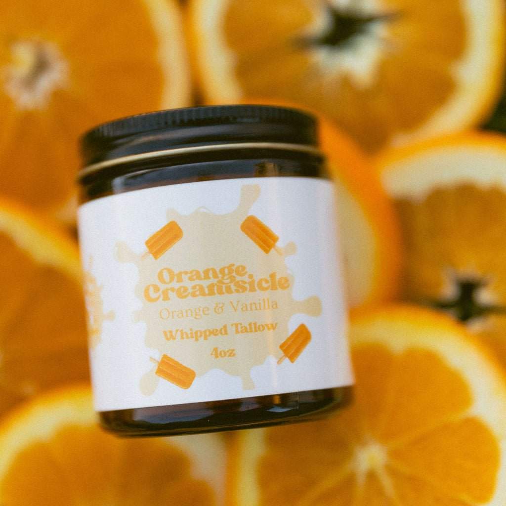 Naturallow Whipped Tallow Moisturizer, Orange Creamsicle jar on orange slices