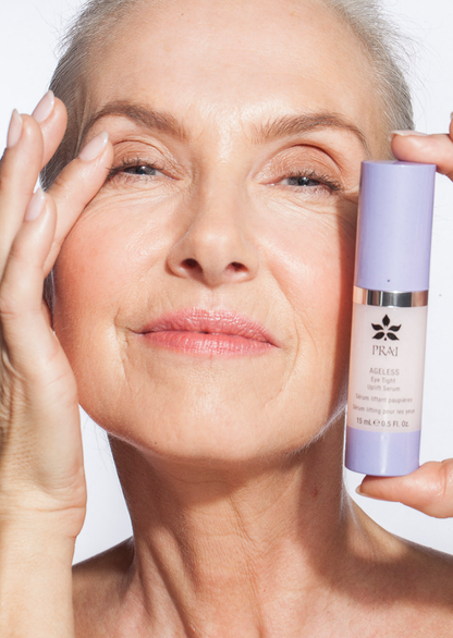 PRAI Beauty Ageless Eye Tight Uplift Serum, woman holding the bottle beside her eye