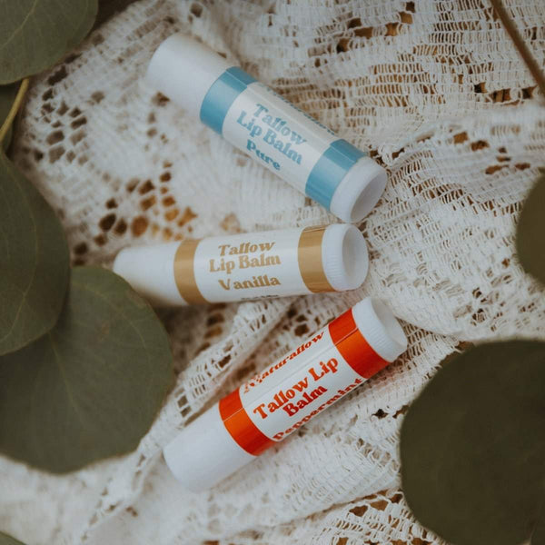 Naturallow Tallow Lip Balm, Pure, Vanilla and Peppermint tubes on white lace with eucalyptus