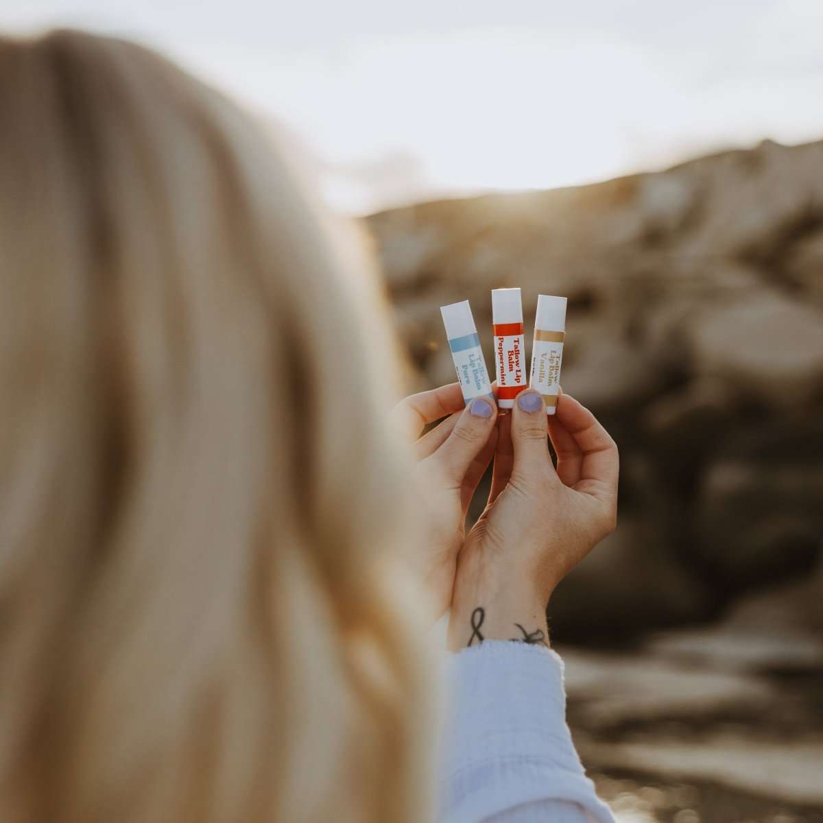 Naturallow Tallow Lip Balm, woman holding three tubes outdoors