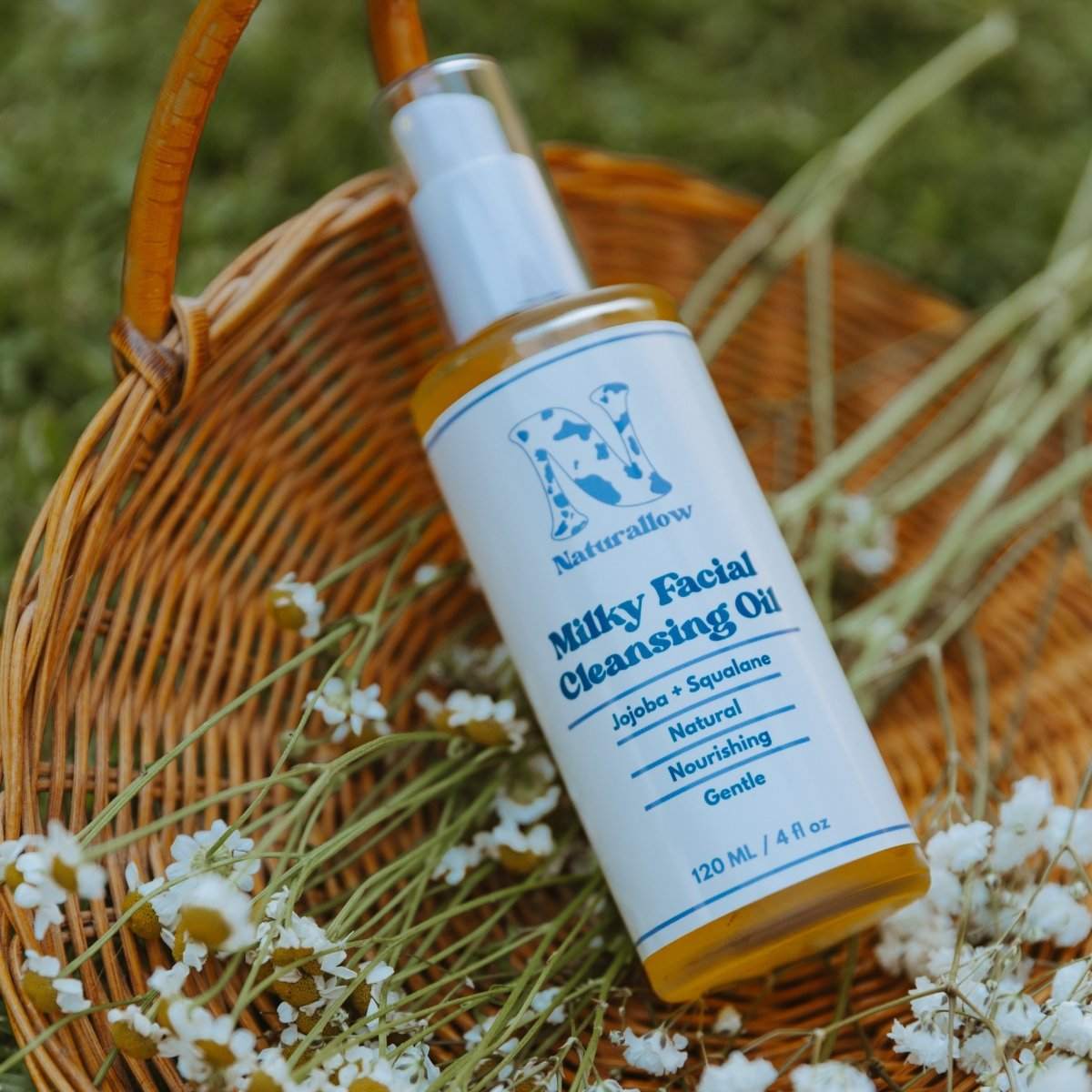 Naturallow Milky Facial Cleansing Oil, bottle in a wicker basket with white flowers