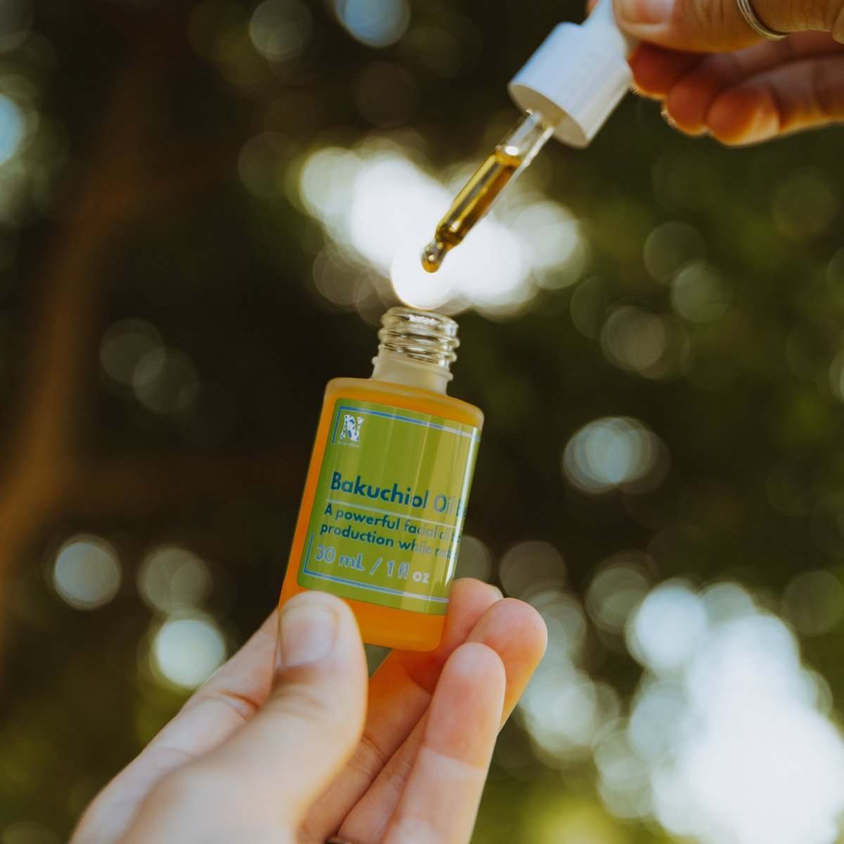 Naturallow Bakuchiol Facial Oil, dropper lifted from the bottle, trees in the background