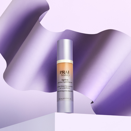 PRAI Beauty Ageless Jawline Uplift Serum, pump bottle on a lilac ribbon backdrop